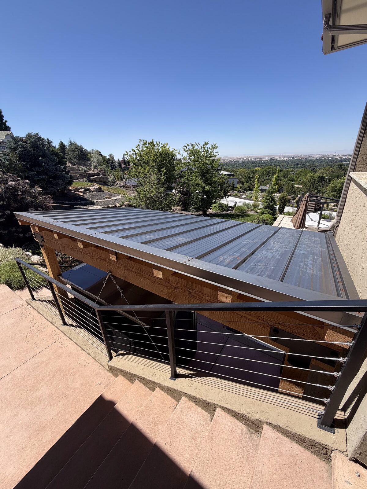 Custom covered patio with a modern metal roof and cedar posts in the Boise foothills