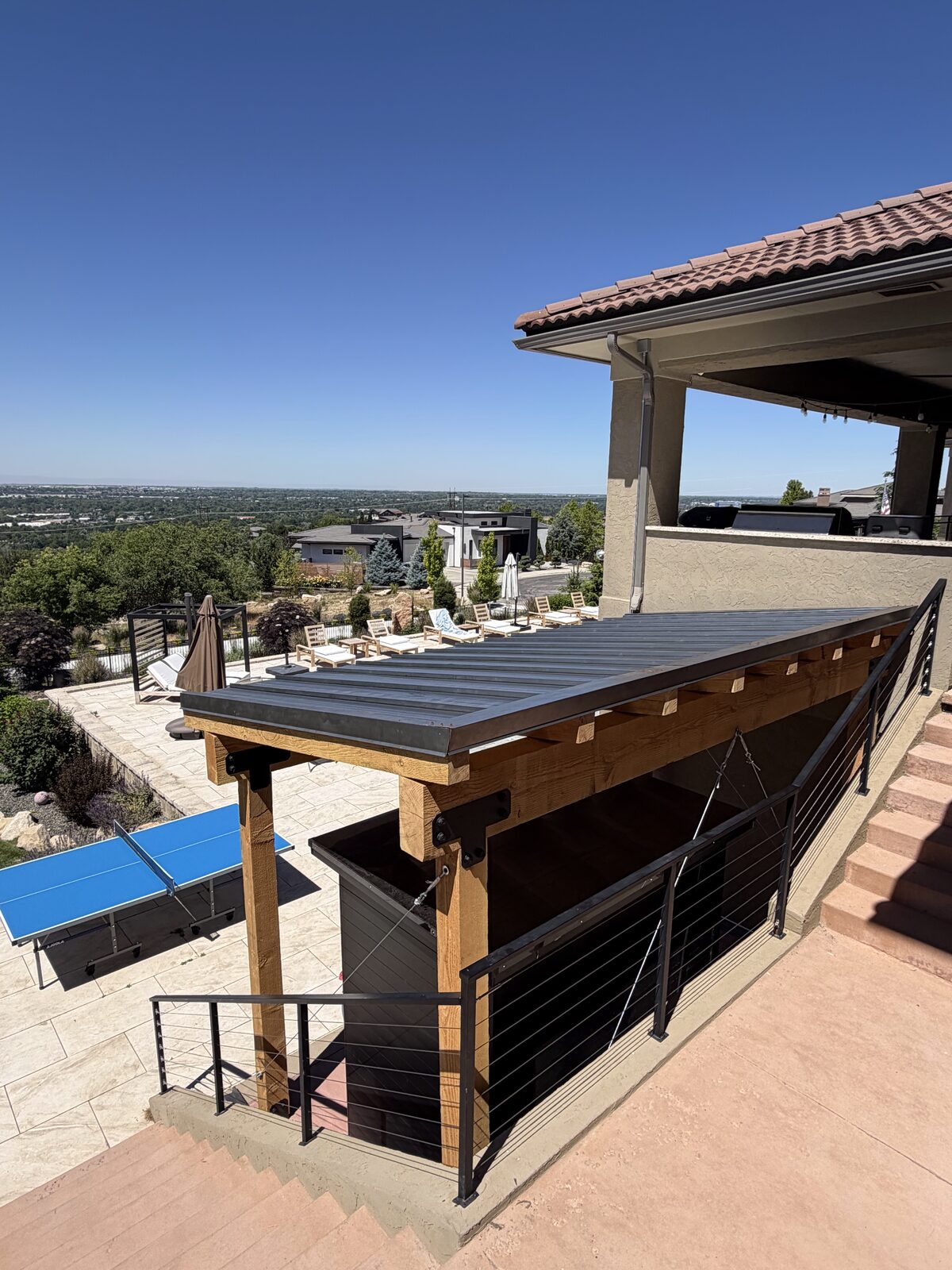 Modern covered patio with a standing-seam metal roof overlooking the Boise foothills